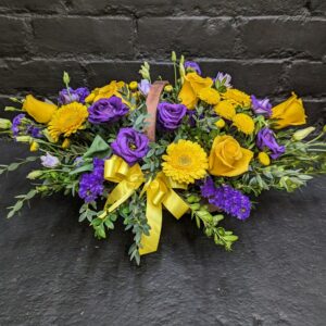 Vibrant arrangement of fresh seasonal flowers in a rustic woven basket, perfect for a cheerful gift or sympathy.