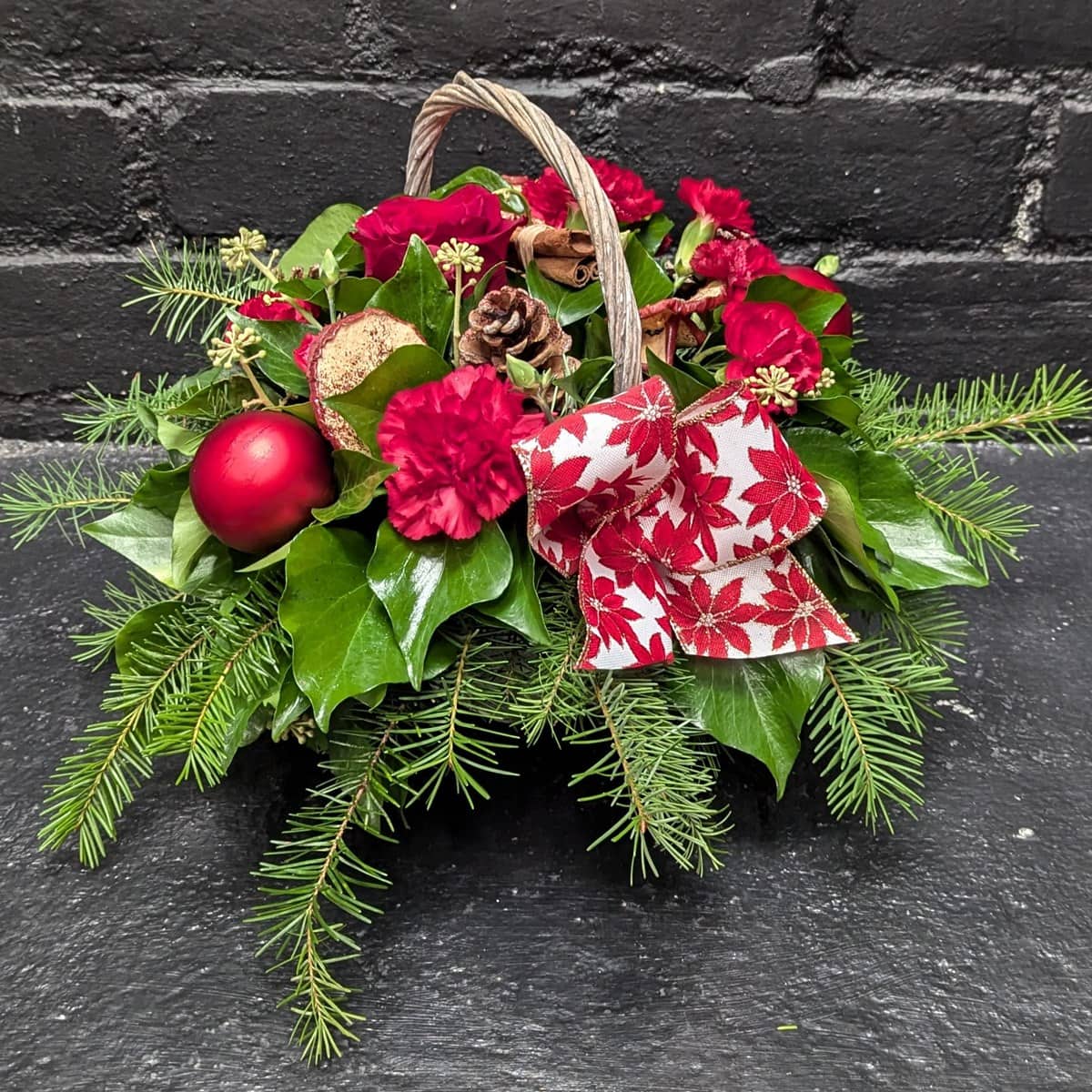 Christmas Flower Basket 1 1 Christmas flower basket with red blooms and greenery – angle view