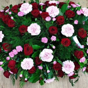 Funeral coffin spray with pink carnations and red carnations