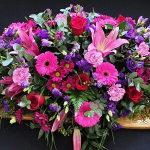Vibrant pink and purple funeral coffin spray arrangement