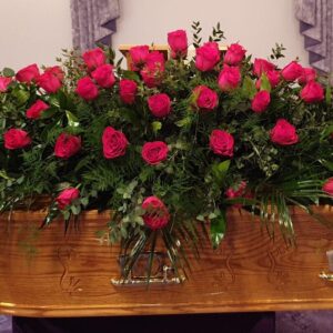 Red rose funeral coffin spray with greenery tribute