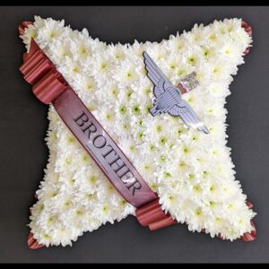 White funeral cushion with ribbon and crest