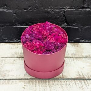 a pink flower in a round box