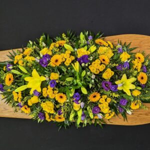 Yellow and purple funeral coffin spray arrangement.
