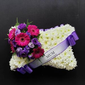 Funeral pillow with white flowers, purple and pink accents