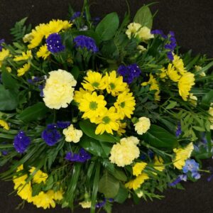 Yellow and purple funeral spray with carnations and daisies