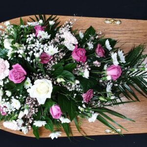 Funeral spray with pink and white roses on a coffin
