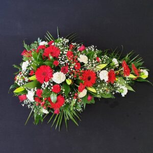 Funeral spray with red gerberas, roses, and white carnations
