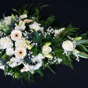 White lily and rose funeral spray with foliage