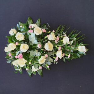 White and pink funeral spray with roses and carnations