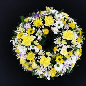 Funeral wreath with yellow, white, and purple flowers