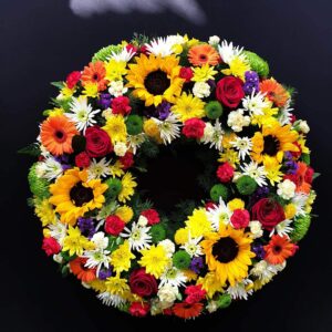 Vibrant funeral flower wreath with sunflowers and roses