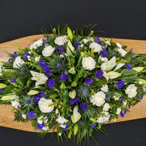 Funeral coffin spray with lilies, carnations, and foliage